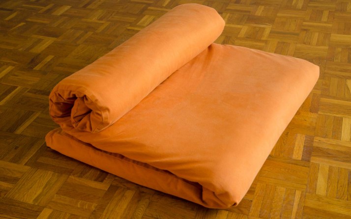 Tapis de yoga futon avec housse en orange en mode méditation.