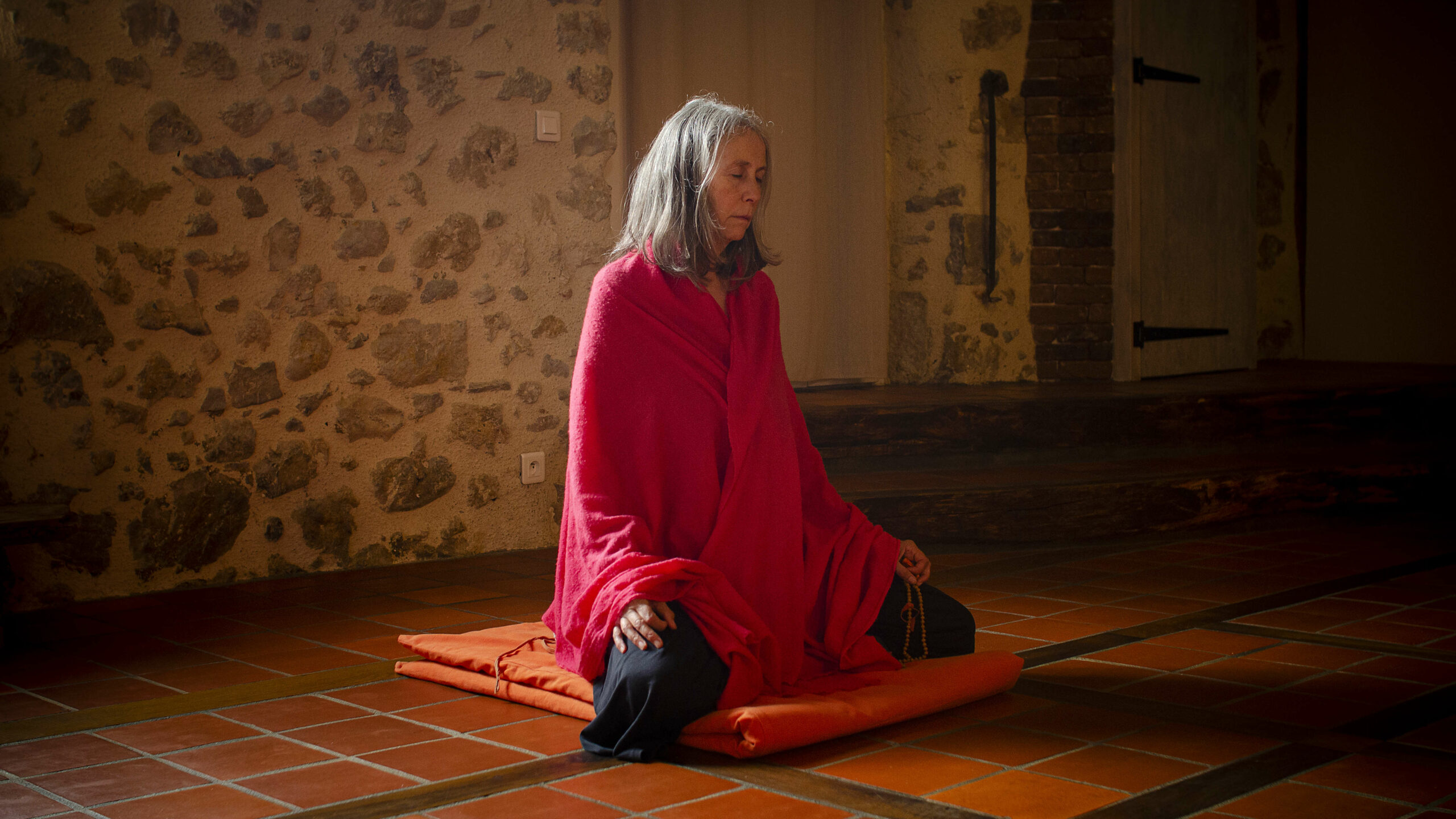 Femme en train de faire la méditation ajapa japa avec un mala dans la main.