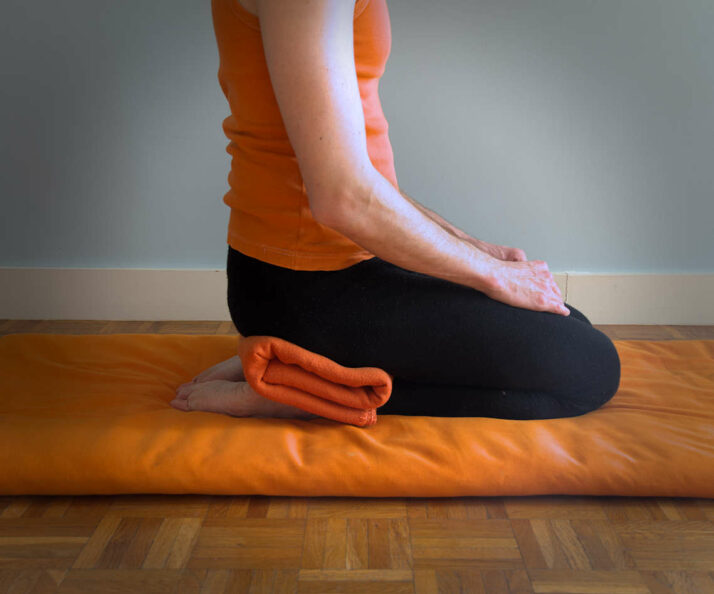 Adaptation de vajrasana avec une couverture entre les fesses et les talons.