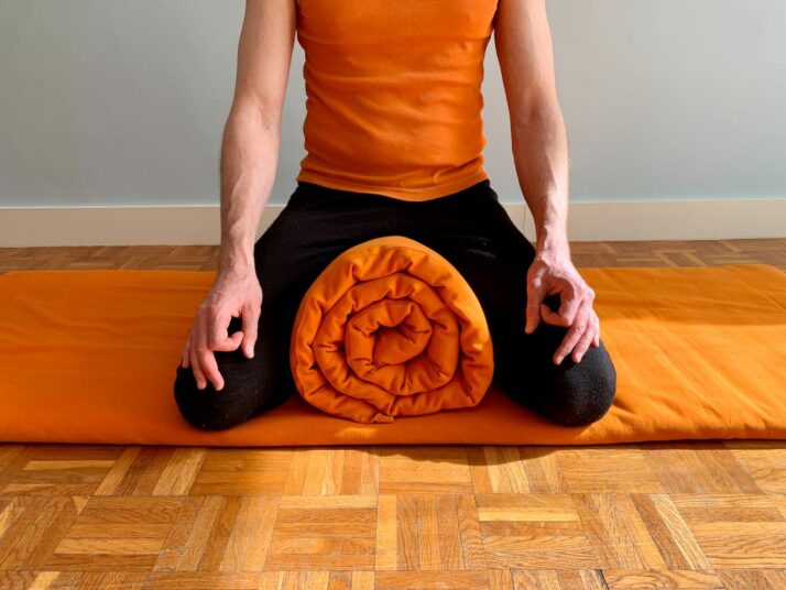 Vajrasana sur un tapis de yoga roulé. 