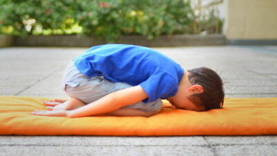 Garçon en balasana, la posture de l'enfant.