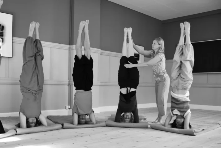 Enseignante de yoga corrige sirsasana.
