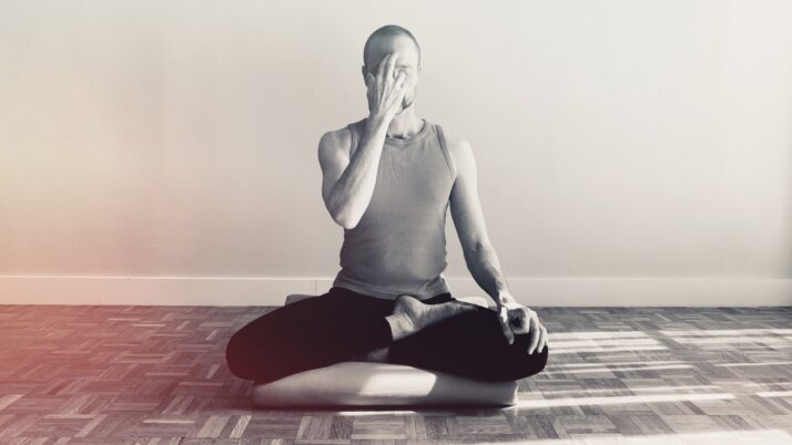 Pratiquant assis en posture méditative pratiquant le pranayama nadi shodhana (respiration alternée).