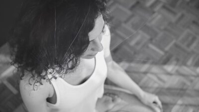 Femme en méditation en noir et blanc avec un effet subtil de fissure évoquant les effets secondaires indésirables de la pratique méditative.