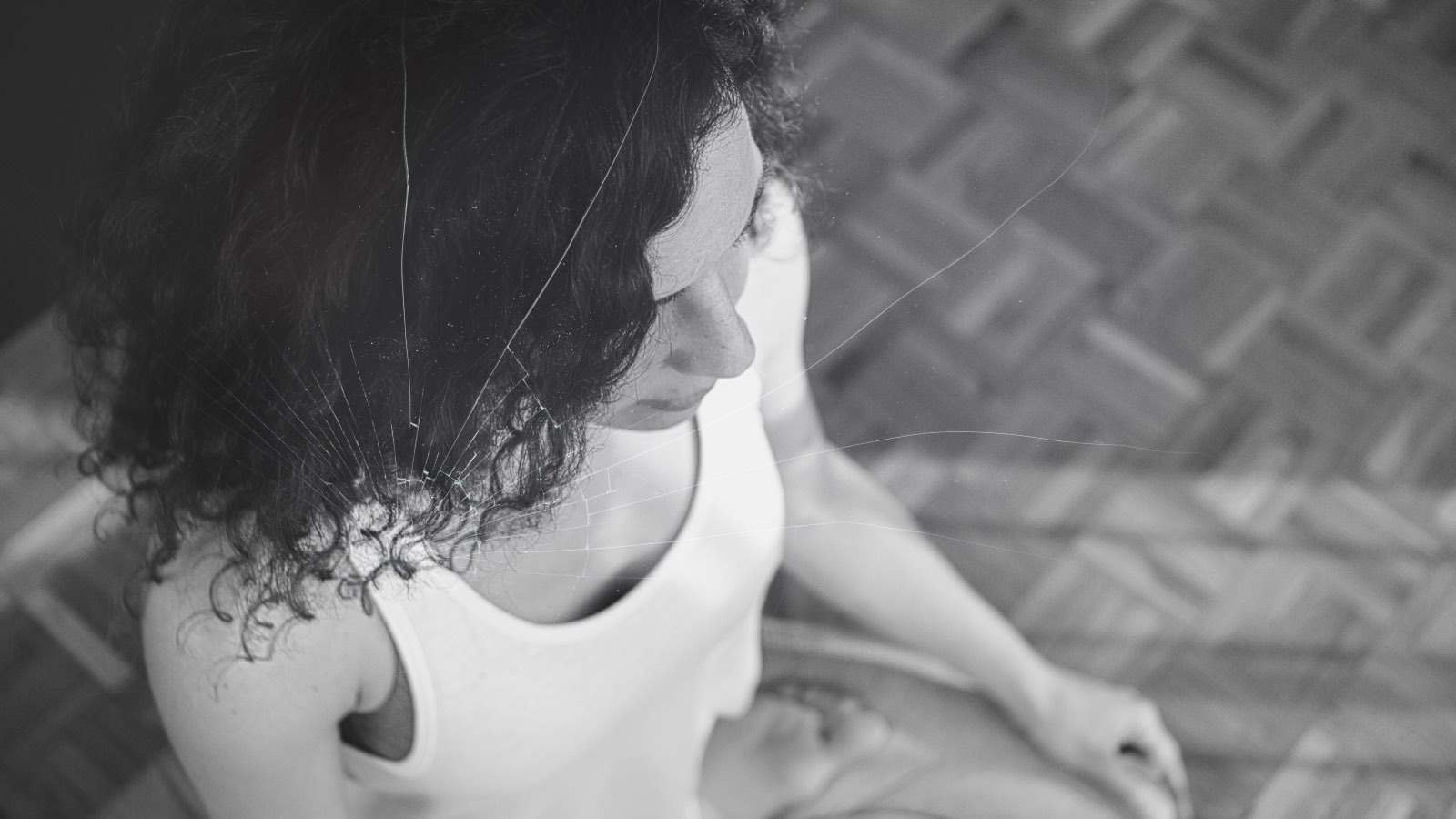 Femme en méditation en noir et blanc avec un effet subtil de fissure évoquant les effets secondaires indésirables de la pratique méditative.