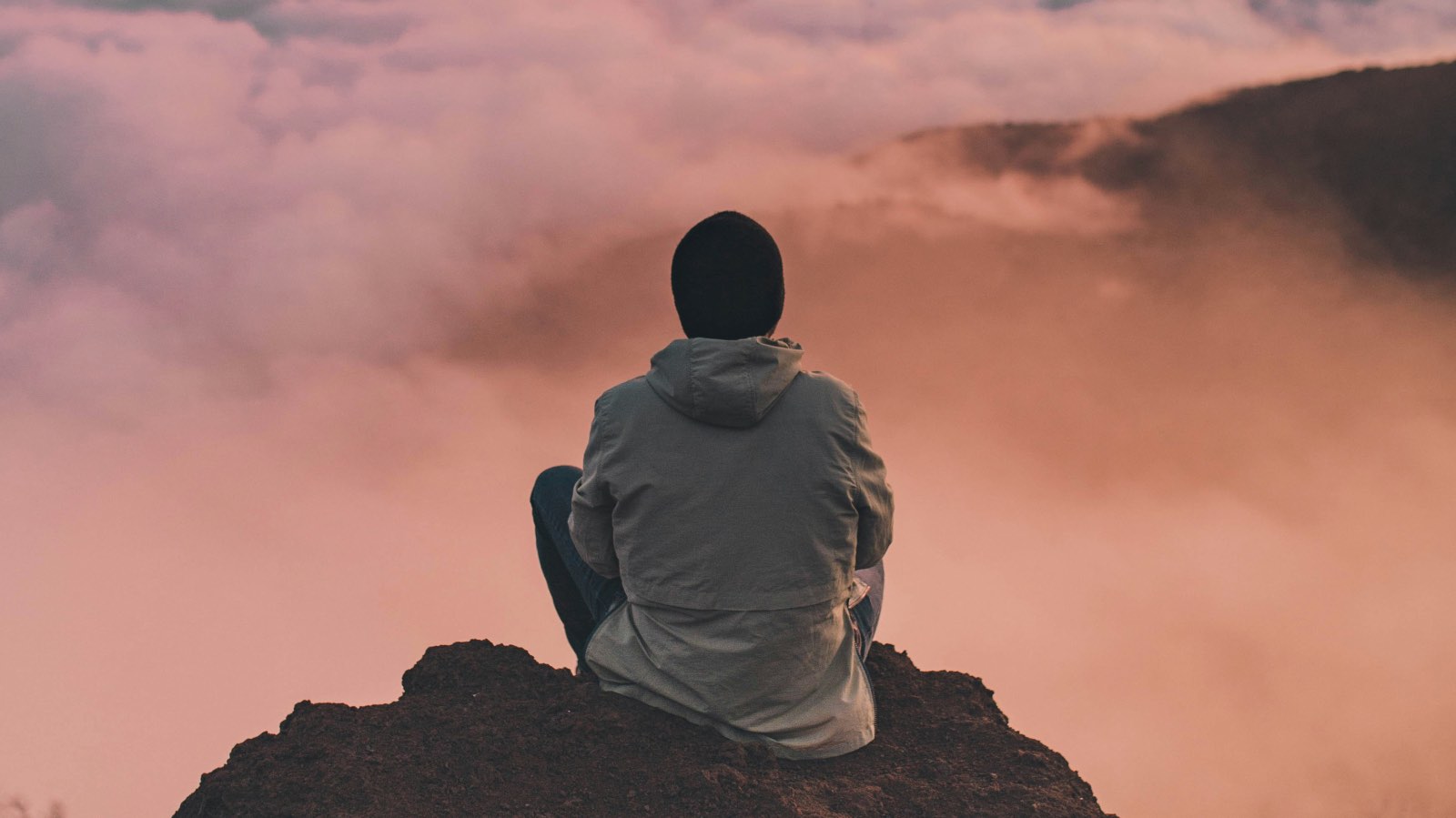 Homme assis en méditation au sommet d'une montagne au-dessus des nuages